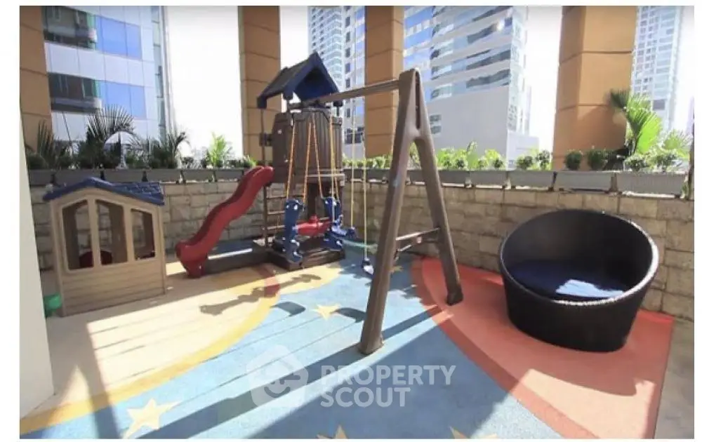 Modern outdoor playground area in urban residential complex with city views.