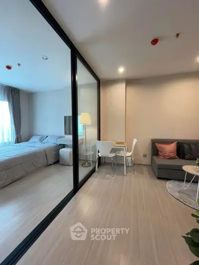 Modern studio apartment with glass partition, cozy living area, and elegant bedroom.
