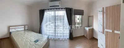 Spacious bedroom with large window and modern furnishings in a bright, airy apartment.