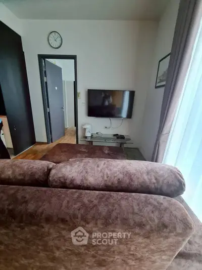 Cozy living room with plush sofa and wall-mounted TV, perfect for relaxation.
