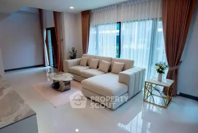 Spacious modern living room with elegant sofa and marble coffee table, featuring large windows and stylish decor.