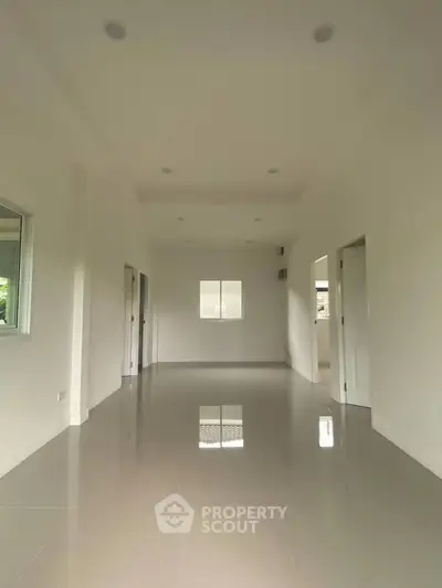 Spacious empty room with glossy tiled floor and white walls, perfect for customization.