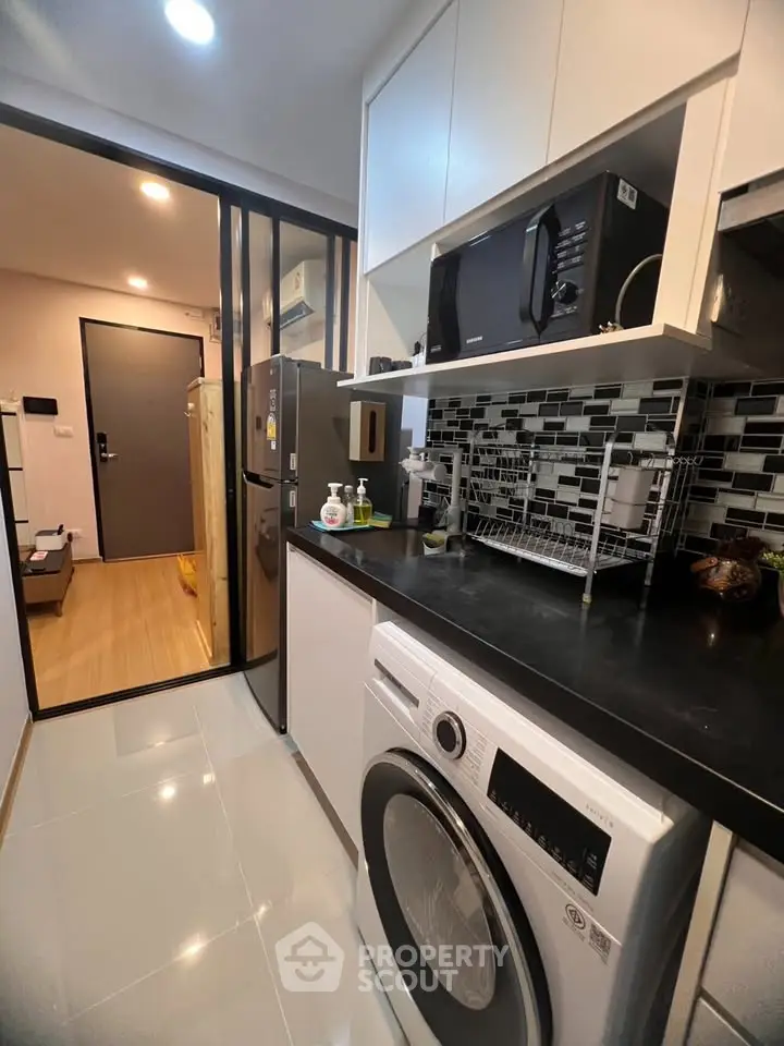Modern kitchen with sleek appliances and stylish backsplash in a contemporary apartment.