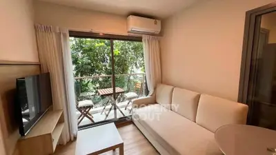 Cozy living room with balcony view, featuring a comfortable sofa and modern decor.
