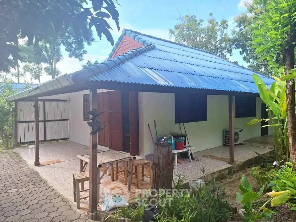 Charming rustic house with blue roof and lush garden, perfect for nature lovers.