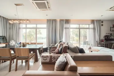Spacious living room with large windows and elegant decor, offering a serene view of the outdoors.
