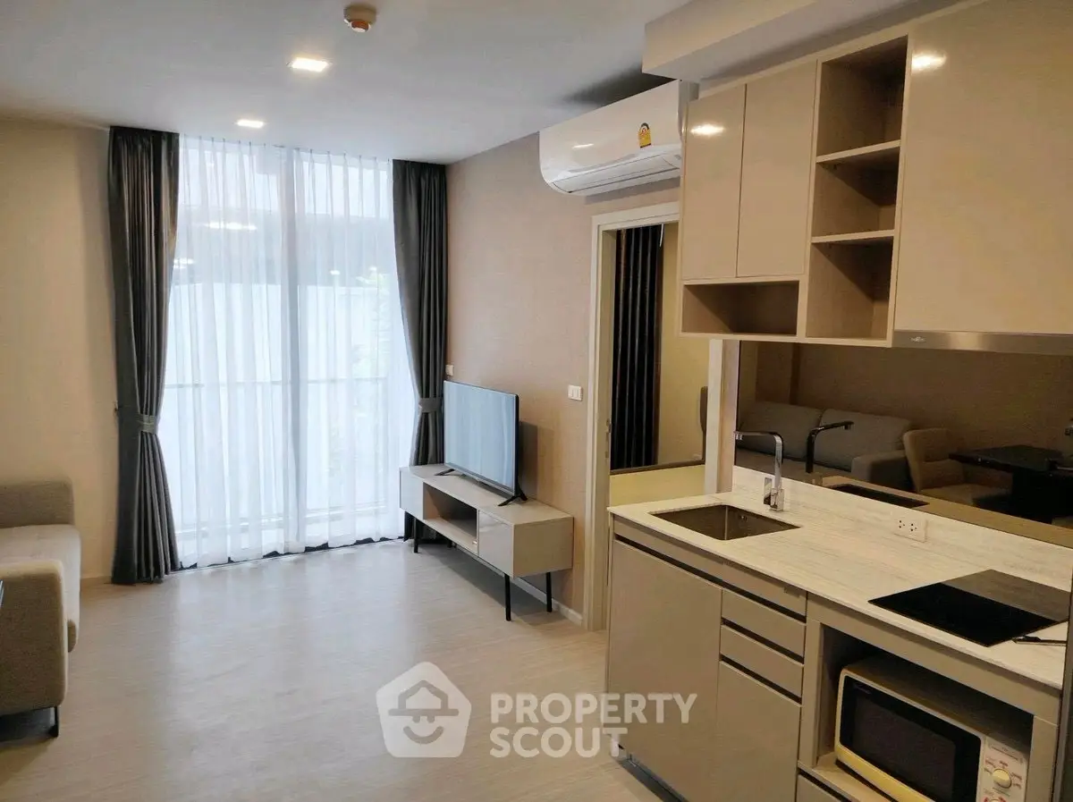 Modern living room with sleek kitchen and large window, perfect for urban living.
