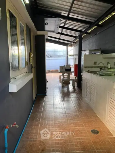 Spacious outdoor area with tiled flooring and covered roof, ideal for laundry or storage.