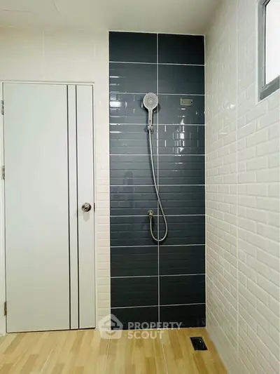 Modern bathroom with sleek black and white tiles and a stylish showerhead.