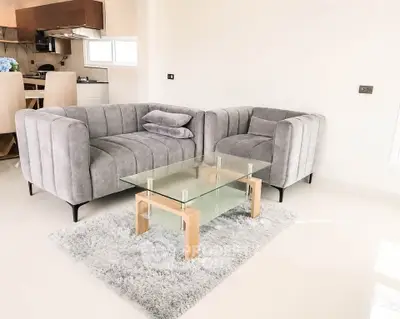 Modern living room with stylish gray sofas and glass coffee table on plush rug