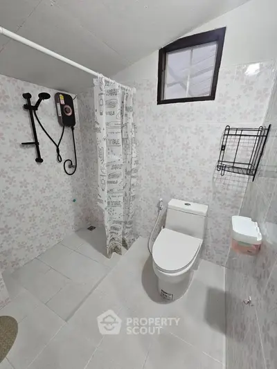 Modern bathroom with floral tiles, shower, and toilet in a cozy real estate property.