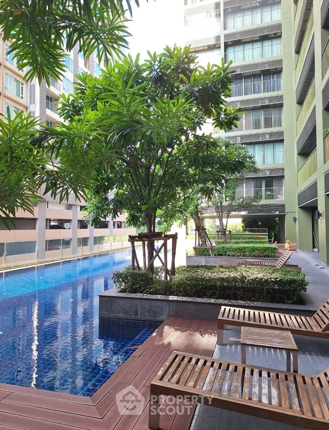 Luxurious condominium pool area with lush greenery and modern design.