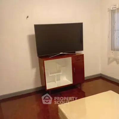 Cozy living room with mounted TV and stylish cabinet on wooden flooring.