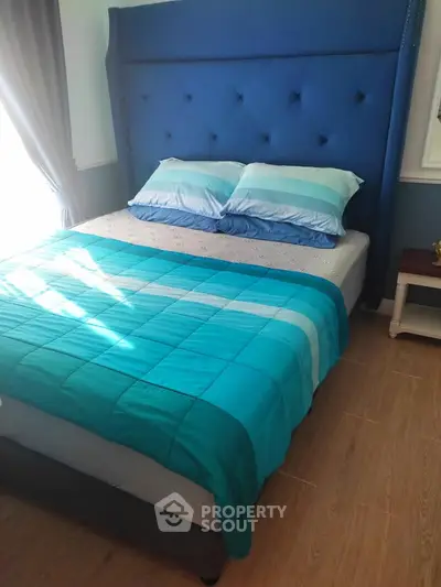 Cozy bedroom with stylish blue headboard and matching bedding, perfect for a restful retreat.