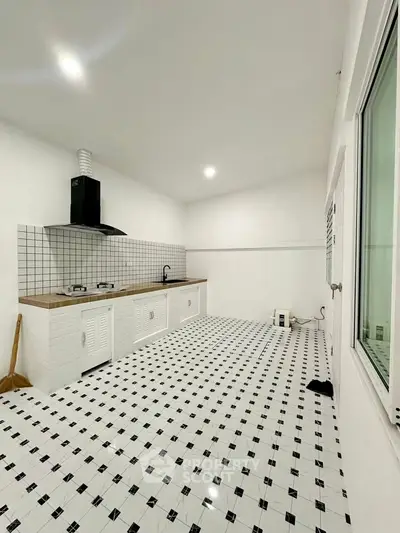 Spacious modern kitchen with sleek white cabinetry and tiled flooring, featuring a gas stove and ample natural light.
