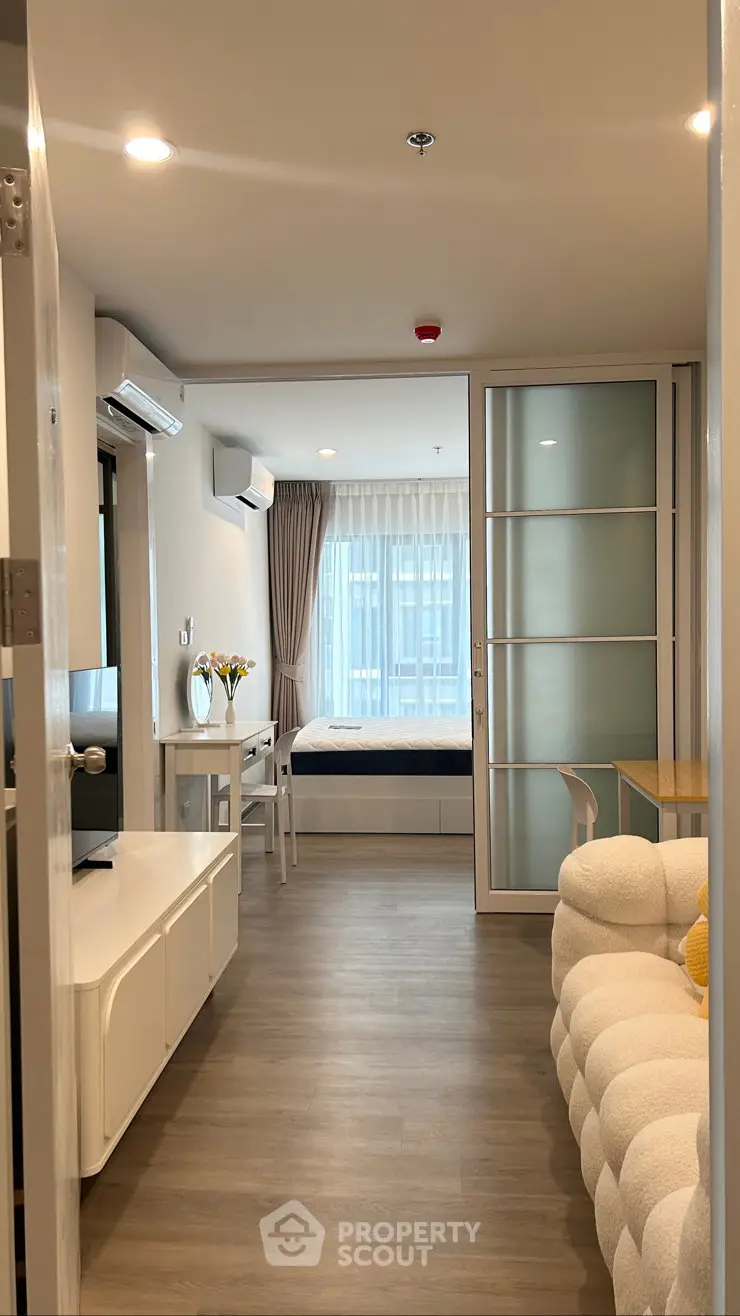 Modern apartment interior with cozy living room and bedroom separated by sliding glass doors.