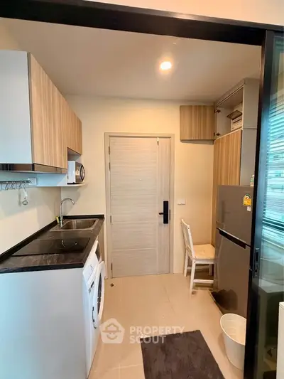 Modern compact kitchen with sleek cabinetry and built-in appliances in a cozy apartment.