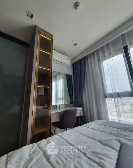 Modern bedroom with city view, featuring sleek furniture and large windows for natural light.