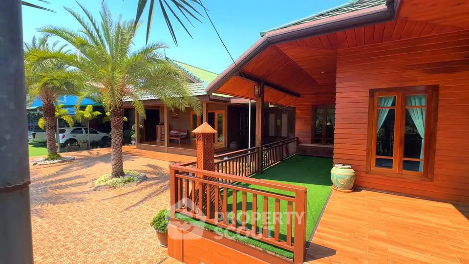 Charming wooden house with lush palm trees and spacious terrace in sunny setting.
