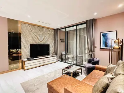 Luxurious living room with modern decor and large glass doors leading to a balcony, perfect for relaxation.