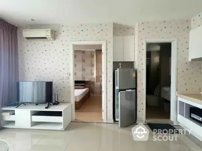 Modern apartment interior with TV, fridge, and bedroom view