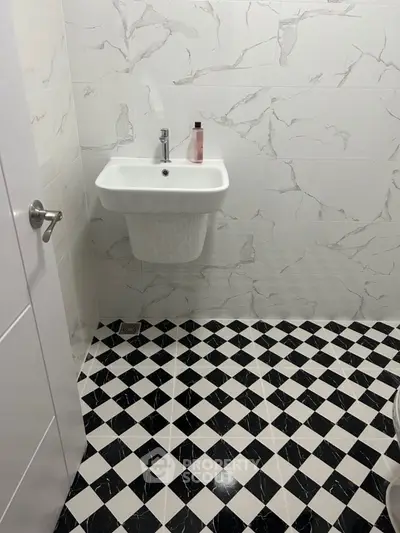 Modern bathroom with stylish black and white checkered floor tiles and elegant wall tiles.