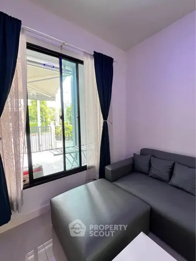 Cozy living room with modern sofa and large window overlooking a balcony, perfect for relaxation.