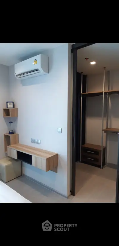 Modern bedroom with built-in desk and walk-in closet, featuring sleek design and air conditioning.