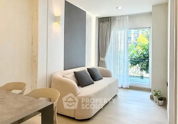 Bright modern living room with cozy sofa and large window overlooking greenery.