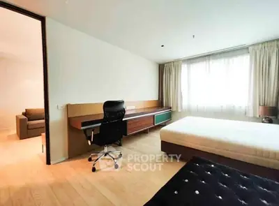 Spacious bedroom with modern desk and large window for natural light.