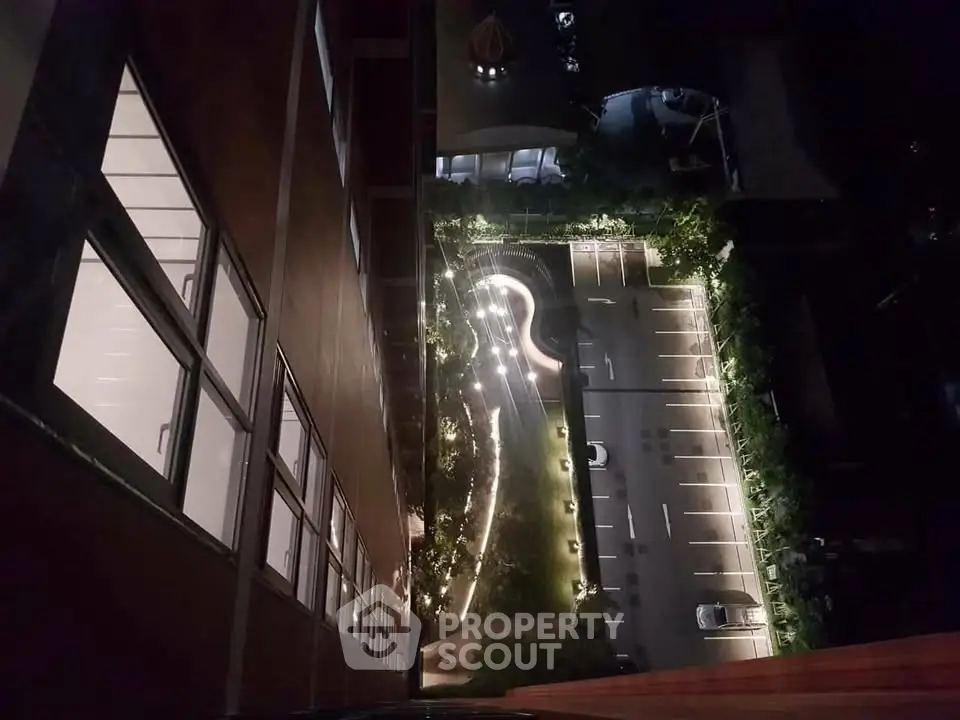 Stunning night view from high-rise building overlooking illuminated parking area.
