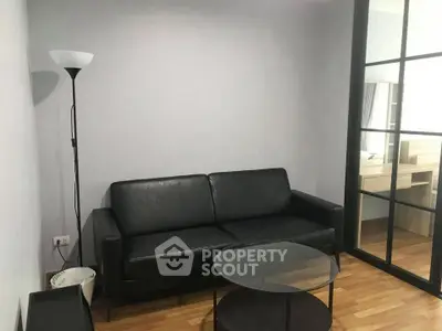 Modern living room with black leather sofa and glass coffee table