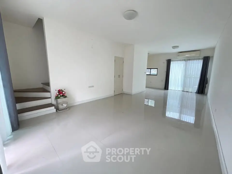 Spacious modern living room with large windows and sleek staircase
