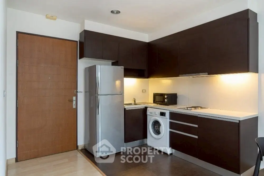 Modern kitchen with sleek cabinets, stainless steel fridge, and washing machine.