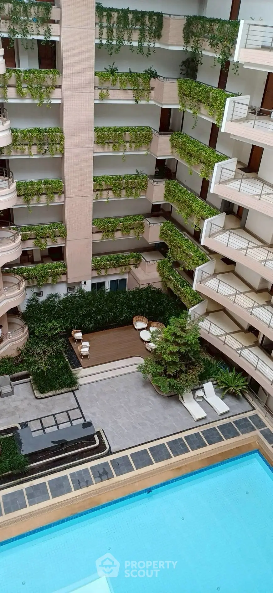 Luxurious apartment complex with lush greenery and inviting swimming pool.