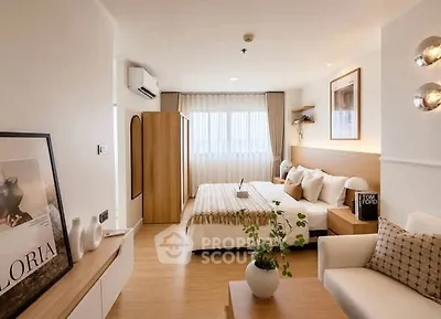 Modern bedroom with stylish decor and natural light, featuring cozy seating and elegant furnishings.