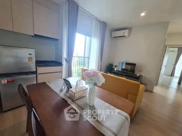 Modern open-layout living room with dining area, featuring stylish furniture and natural light.