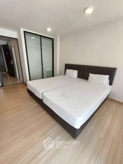 Spacious bedroom with twin beds and modern sliding closet doors, perfect for comfortable living.