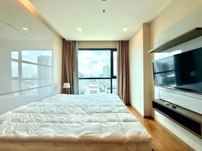 Spacious bedroom with city view, modern furnishings, and natural light.