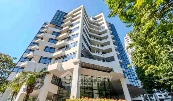 Stunning modern apartment building with glass facade and lush greenery