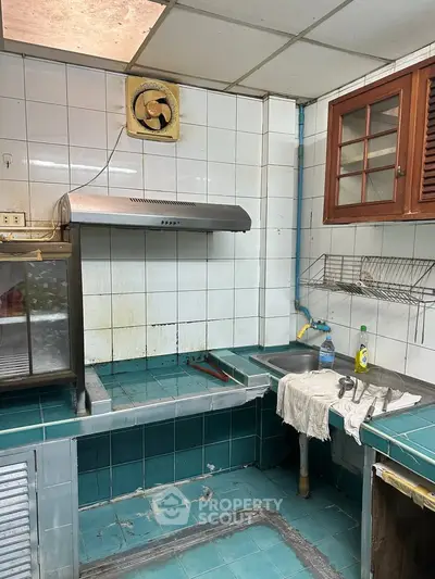 Charming vintage kitchen with teal tiles and rustic wooden cabinets, perfect for renovation enthusiasts.
