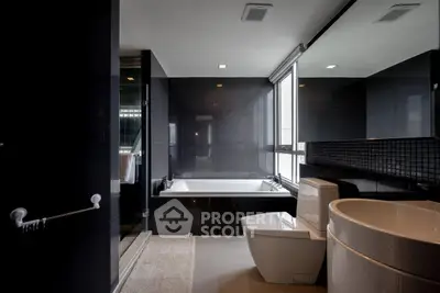 Luxurious modern bathroom with sleek black tiles and large bathtub