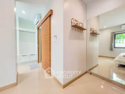 Spacious modern bedroom with large mirror and sliding wooden door
