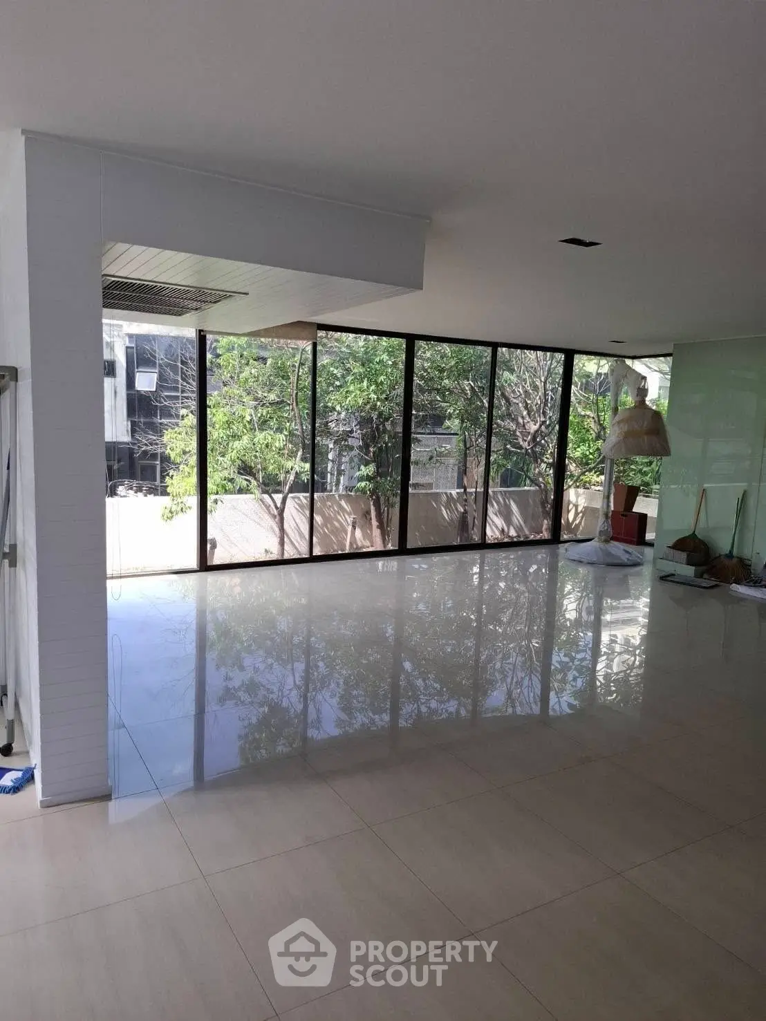 Spacious modern living room with large windows offering lush garden views, perfect for relaxation and entertaining.