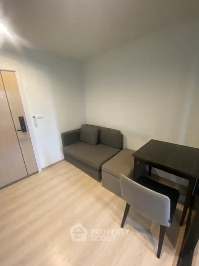 Cozy living room with modern furniture and wooden flooring in a compact apartment.