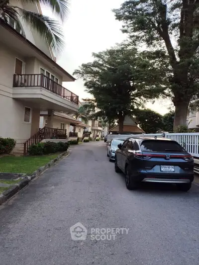 Charming residential street with parked cars and lush greenery, showcasing suburban living at its finest.