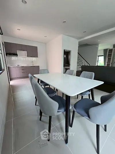 Modern dining area with sleek table and chairs, open kitchen layout, and stylish decor.