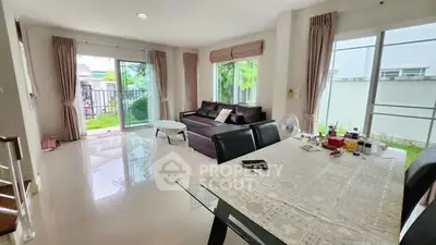 Spacious living room with modern furniture and large windows offering garden views.