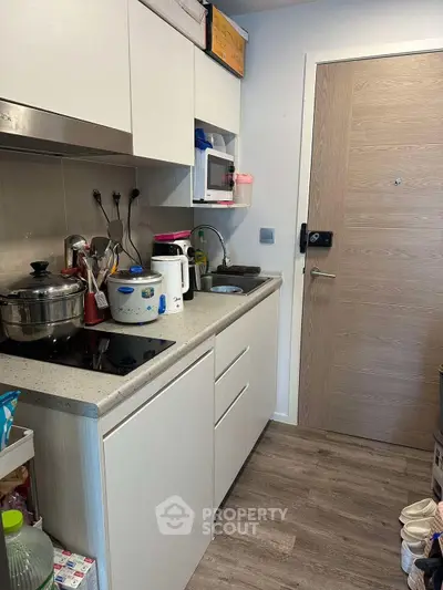 Compact kitchen with modern appliances and sleek cabinetry in a cozy apartment setting.