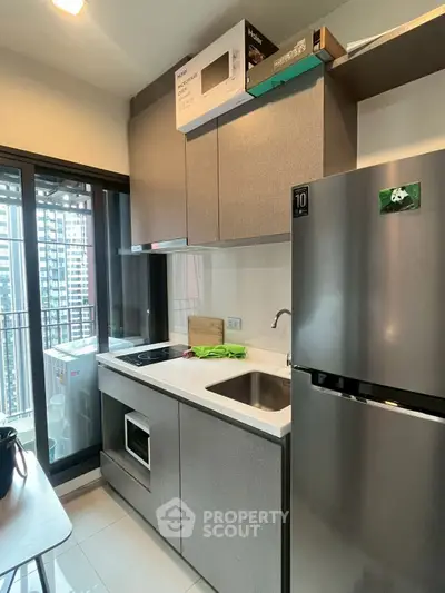 Modern kitchen with sleek appliances and balcony view in urban apartment